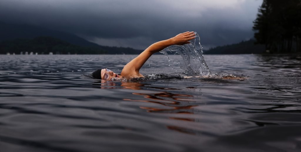 swimmer swimming across a lake photography - jakob owens retouching bill greenwood